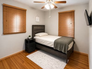 A bedroom with a bed, nightstand, ceiling fan, and wooden blinds. - Enjoyable 3-bedroom house with AC in charming Nashville (Nashville)