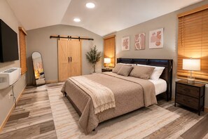 A bedroom with a bed, bedside tables, a TV, a wardrobe, and artwork on the wall. - Enjoyable 3-bedroom house with AC in charming Nashville (Nashville)