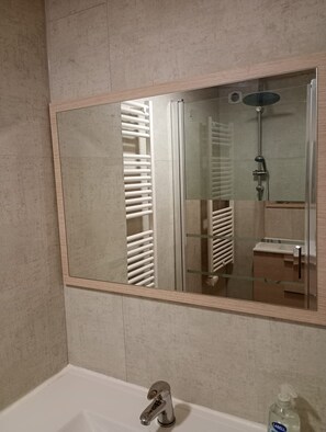 Une salle de bain avec un grand miroir, une baignoire, une douche et des toilettes.