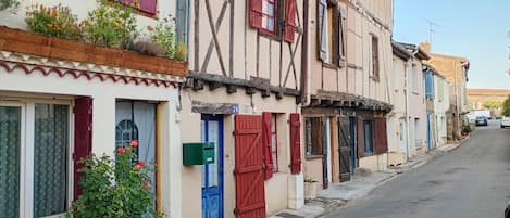 A row of traditional European-style buildings with timber framing, shutters, and a narrow street.