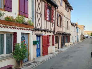 Une rangée de bâtiments de style européen traditionnel, caractérisés par une structure en bois apparent, des volets et une rue étroite.