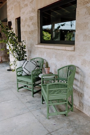 Two green wicker chairs with cushions, a small potted cactus, and a window with a view of greenery. - Hill Country Oasis: 8‑Bedroom Resort with Pool, Scenic Views & Gathering Spaces (Dripping Springs)
