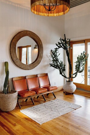 A room with a wooden bench, a round mirror, a cactus plant, and a large potted plant. - Hill Country Oasis: 8‑Bedroom Resort with Pool, Scenic Views & Gathering Spaces (Dripping Springs)