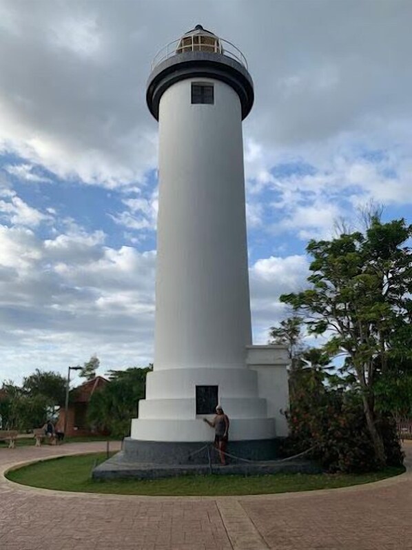Ein hoher, weißer Leuchtturm mit kreisförmigem Fundament und einer kleinen Tür am unteren Ende.