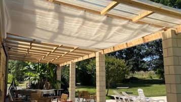 Un patio exterior con zona de estar techada, una mesa de comedor y una parrilla.