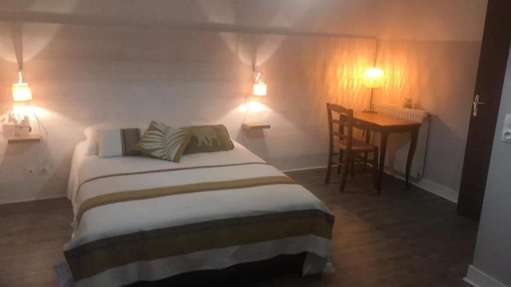 A bedroom with a bed, bedside lamps, a desk, and a chair.