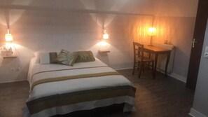 Un dormitorio con cama, lámparas de noche, escritorio y una silla.