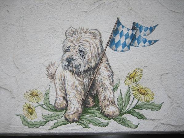 A wall with a painting of a dog with a flag. - Grieshaber Haisl (Bad Bayersoien)