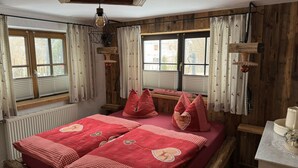 A room with a bed, windows, wooden walls, and a ceiling light fixture. - Grieshaber Haisl (Bad Bayersoien)