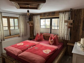 A room with a bed, windows, wooden walls, and a ceiling light fixture. - Grieshaber Haisl (Bad Bayersoien)