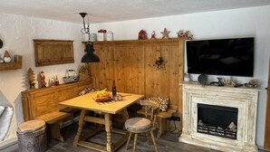 A cozy room with a wooden dining table, benches, a fireplace, a television, and holiday decorations. - Grieshaber Haisl (Bad Bayersoien)