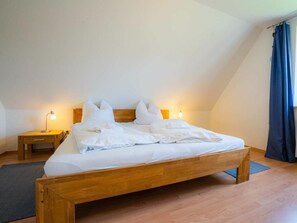 A single bed in a room with a sloped ceiling, a bedside table, and a lamp. - House Section 152a "At the Lighthouse" (St. Peter-Ording)