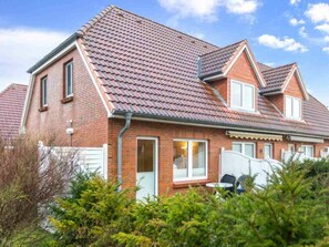 A two-story house with a red-tiled roof, brick walls, and a white fence. - House Section 152a "At the Lighthouse" (St. Peter-Ording)