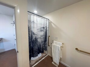 Casa de banho com cortina de chuveiro com motivos florestais, um porta-toalhas com toalha branca e um corrimão.
