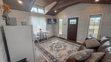 A cozy interior with a brown leather sofa, a patterned rug, and a wooden ceiling.