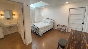 A bedroom with a bed, a small table, a bench, a mirror, and a door. - Quaint Cabin on 30 acres in Springfield (Springfield)