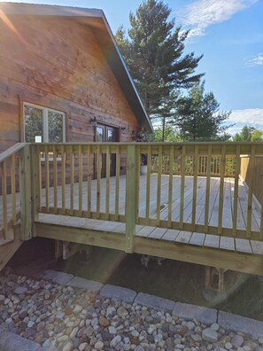 A wooden deck with a railing leading to a building with a sloped roof. - Spacious 7-bedroom house in serene Arkdale with AC (Arkdale)