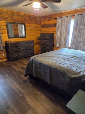 A bedroom with a bed, dresser, mirror, and ceiling fan. - Spacious 7-bedroom house in serene Arkdale with AC (Arkdale)