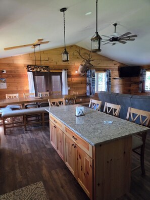 A spacious kitchen with wooden cabinets, a granite countertop island, and a ceiling fan. - Spacious 7-bedroom house in serene Arkdale with AC (Arkdale)