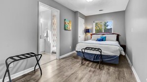 Een slaapkamer met een bed, een raam en een deur die naar een andere kamer leidt.