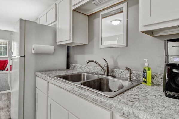 A kitchen with a double sink, a refrigerator, and a hand soap dispenser.