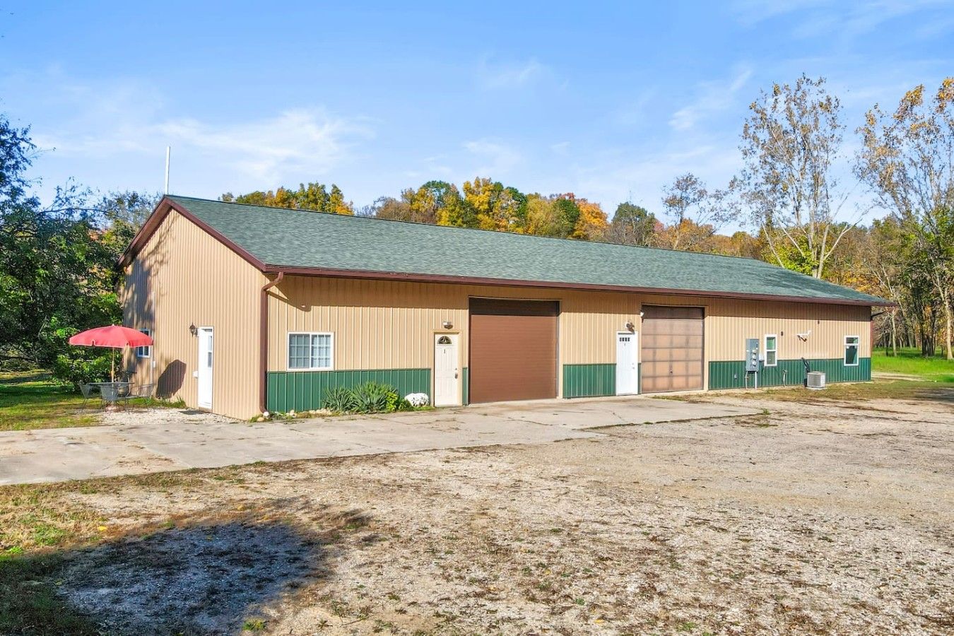 A single-story building with a green roof, a brown door, and a small attached garage.