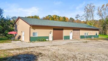 A single-story building with a green roof, a brown door, and a small attached garage.