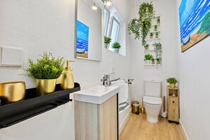 A modern bathroom with a white sink, gold fixtures, and a wooden vanity. - Luxury Villa Costabella Marbella—Pool, Jacuzzi, and Sauna—400 m from the Beach (Marbella)