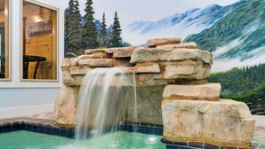 Ein Pool mit Wasserfall, umgeben von einem Wandbild einer Berglandschaft.