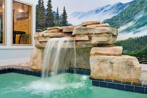 A pool with a waterfall feature, surrounded by a mural of a mountainous landscape. - You Ultimate Smoky Mountain Escape (Gatlinburg)