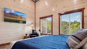 Ein Schlafzimmer mit einem großen Bett, einem Sessel, einem Schreibtisch und einem Gemälde an der Wand.
