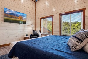 A bedroom with a large bed, a chair, a desk, and a painting on the wall. - You Ultimate Smoky Mountain Escape (Gatlinburg)