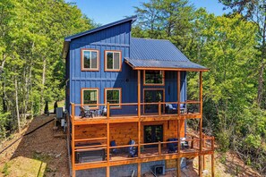 A multi-story wooden cabin with a balcony, surrounded by trees. - You Ultimate Smoky Mountain Escape (Gatlinburg)