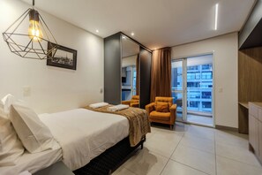 Quarto de hotel moderno com cama, poltrona, espelho grande e vista para a cidade.