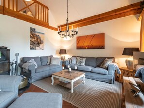 A cozy living room with a sectional sofa, a wooden coffee table, and a chandelier. - Holiday Home With 2 Bedrooms (St. Peter-Ording)