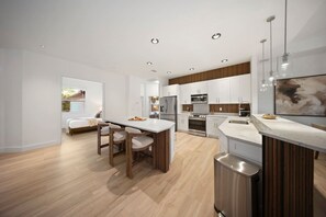 Una cocina moderna con una isla central, piso de madera y electrodomésticos integrados.