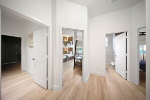 Un interior moderno con un pasillo que conduce a un dormitorio con literas y un baño con bañera.