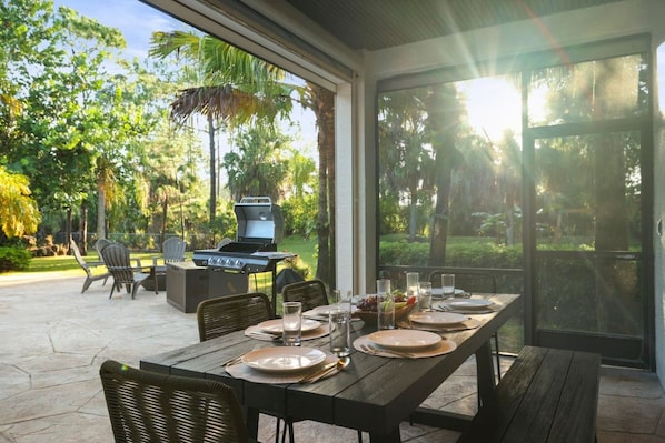 Un área de comedor al aire libre con una parrilla, sillas y una mesa para dos.