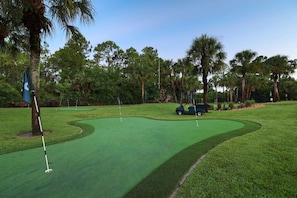 Un campo de golf con un fairway verde, búnkeres de arena y un carrito de golf.