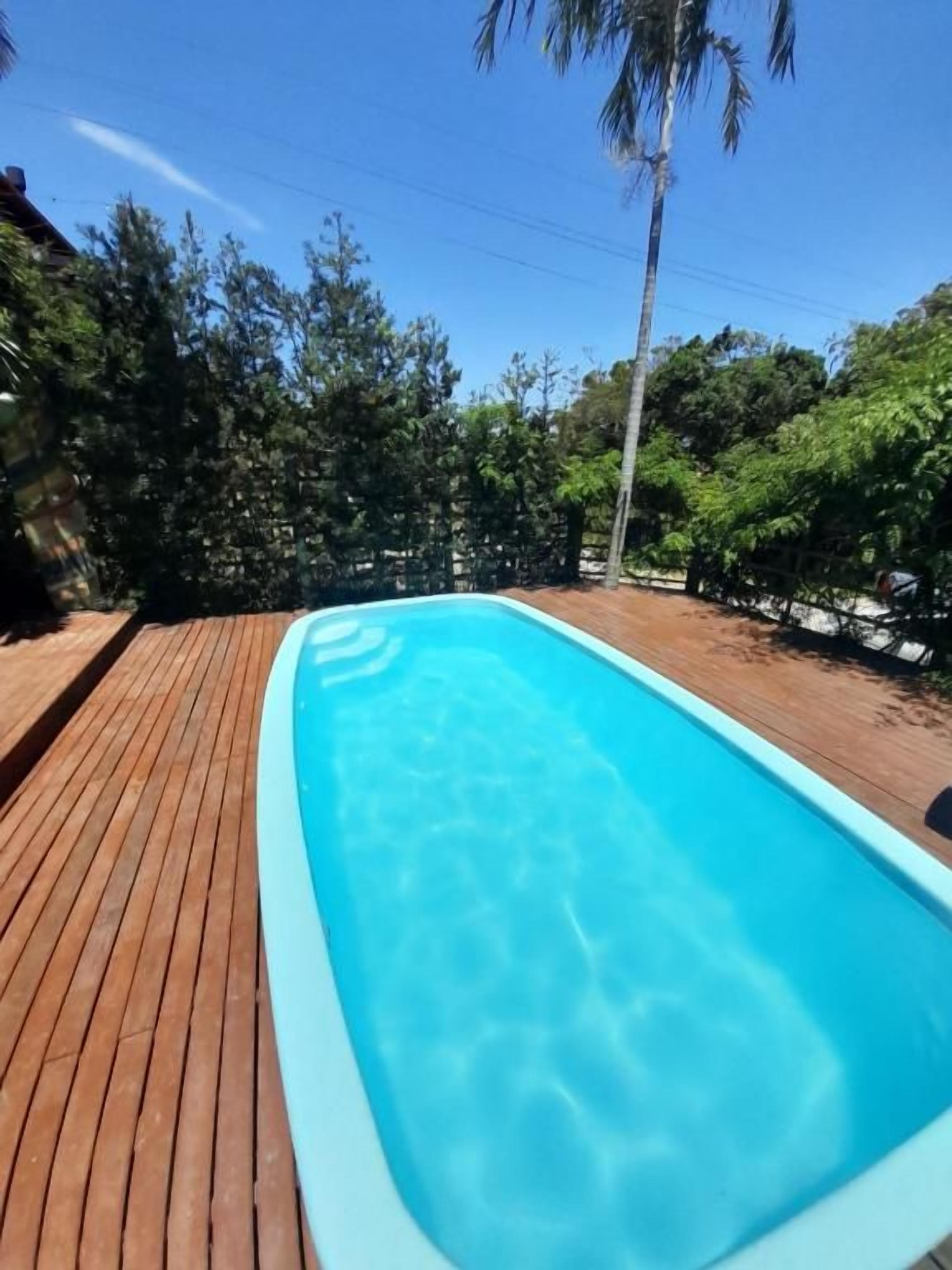 Une piscine rectangulaire à l’eau d’un bleu cristallin, entourée d’une terrasse en bois.