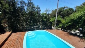 A rectangular swimming pool with clear blue water, surrounded by a wooden deck. - Pousada Baia Rosa (Imbituba)