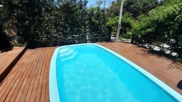Une piscine rectangulaire à l’eau d’un bleu cristallin, entourée d’une terrasse en bois.