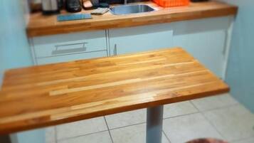 Una cocina con encimera de madera, un lavamanos y dos taburetes.