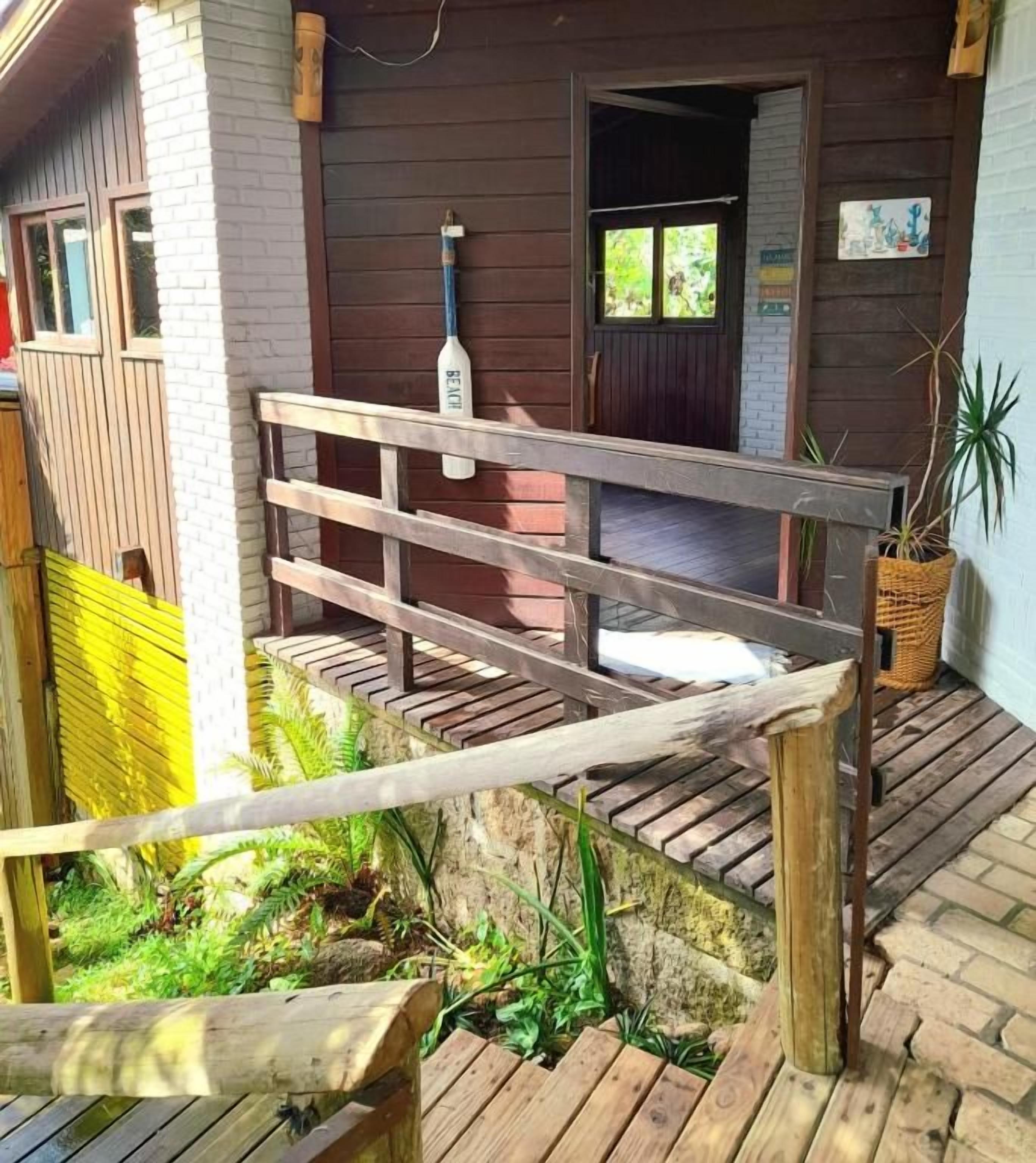 Una terraza de madera que conduce a un edificio con una puerta y ventanas.