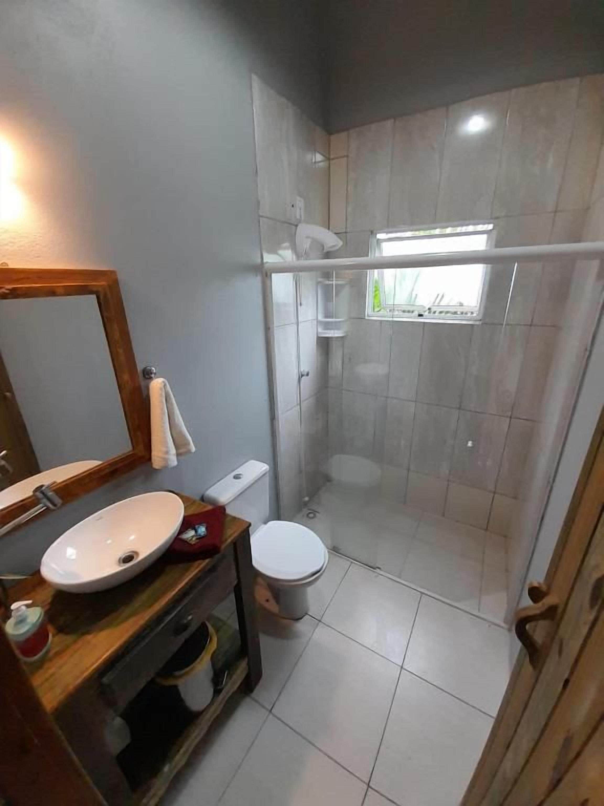 Et badeværelse med bruser, toilet og håndvask.