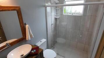 Et badeværelse med bruser, toilet og håndvask.