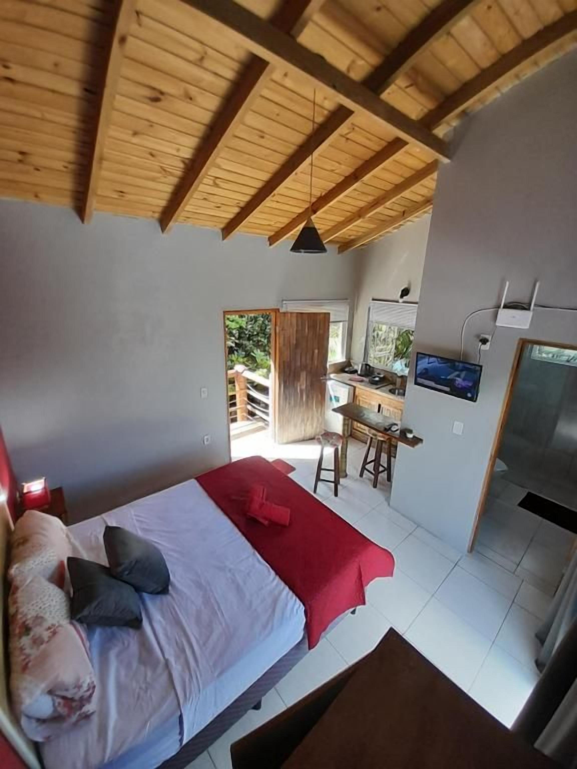 Ein Schlafzimmer mit einem Bett, einer roten Decke und einer Holzbalkendecke.