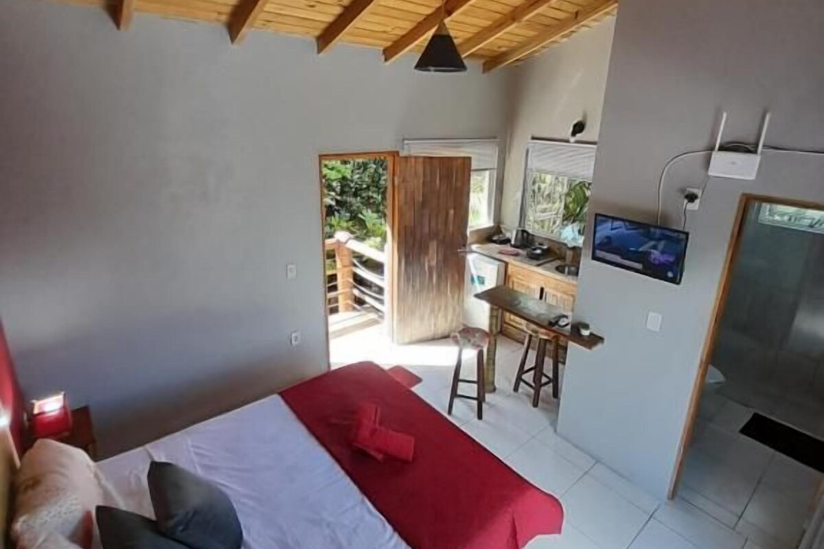 Ein Schlafzimmer mit einem Bett, einer roten Decke und einer Holzbalkendecke.
