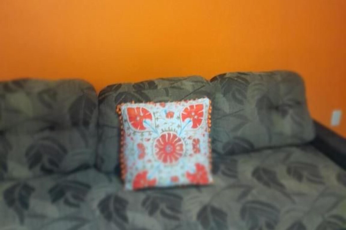 Ein Sofa mit einem gemusterten Kissen vor einer orangefarbenen Wand.