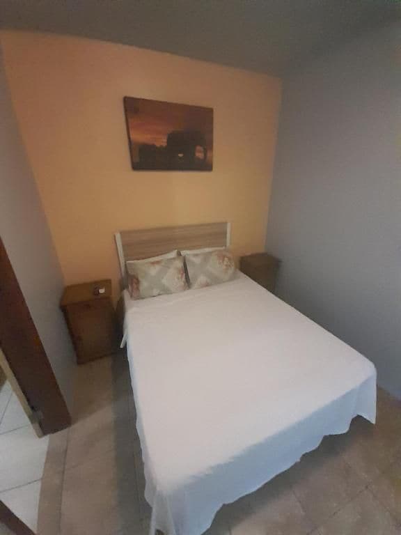 Une chambre à coucher avec un lit, une table de chevet et un tableau accroché au mur.